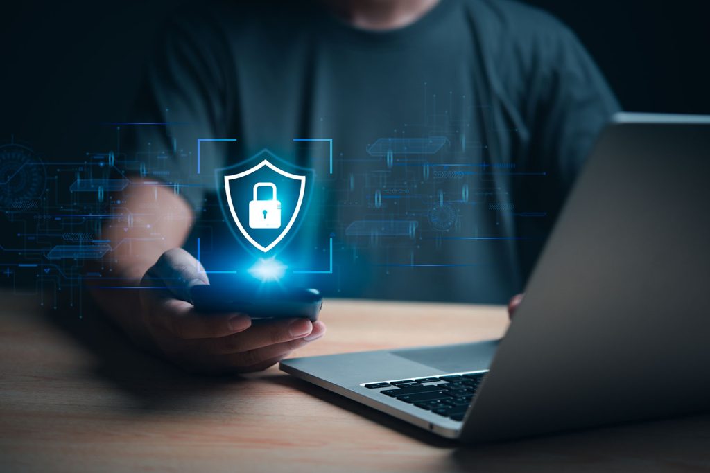 Hand holding phone with laptop